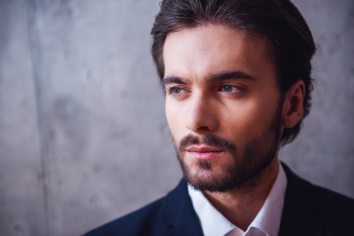 Portrait of handsome confident businessman with bristle, in suit, on gray background