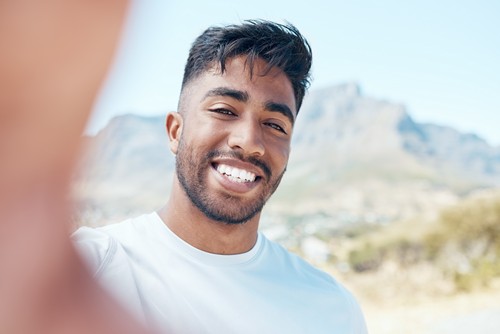 Portrait of a mixed race male taking a selfie and smiling during a workout outside in nature. India.